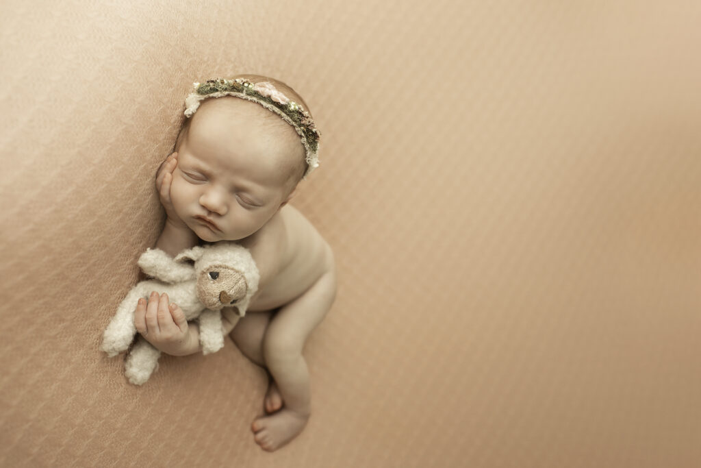 A precious newborn girl curled up on a pink blanket, showcasing her delicate features in a simple and timeless pose by Chunky Monkey Photography