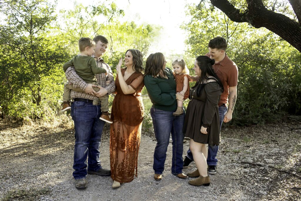 Family portrait session at Eagle Mountain Park in Azle, Texas, capturing the family surrounded by the park’s stunning natural beauty. The group poses against the backdrop of serene lakes, towering trees, and scenic trails. The warm sunlight filters through the foliage, creating a peaceful and picturesque atmosphere. With the tranquil landscape and the family’s joyful connection, the photo session is filled with memorable moments in this beautiful outdoor setting