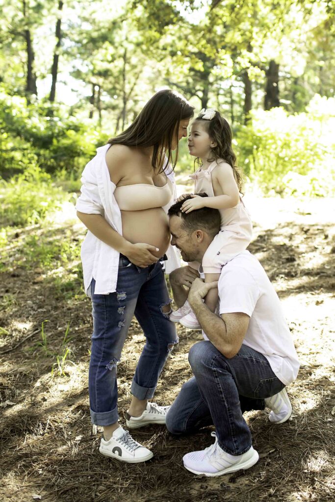 Expecting parents snuggling with their daughter, sharing a joyful and loving moment during a maternity photoshoot