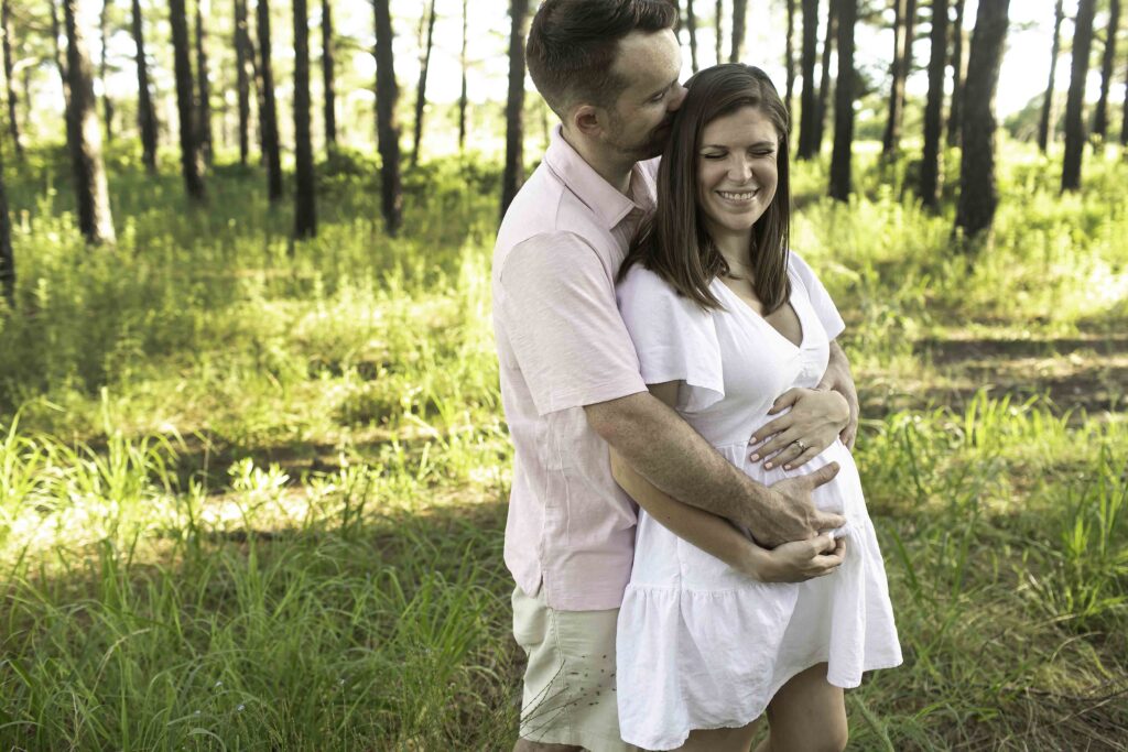 Expecting couple smiling and laughing while snuggling close, capturing a tender and joyful maternity session