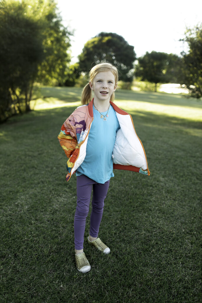 Smiling 6-year-old girl in a vibrant jacket, playing at the park