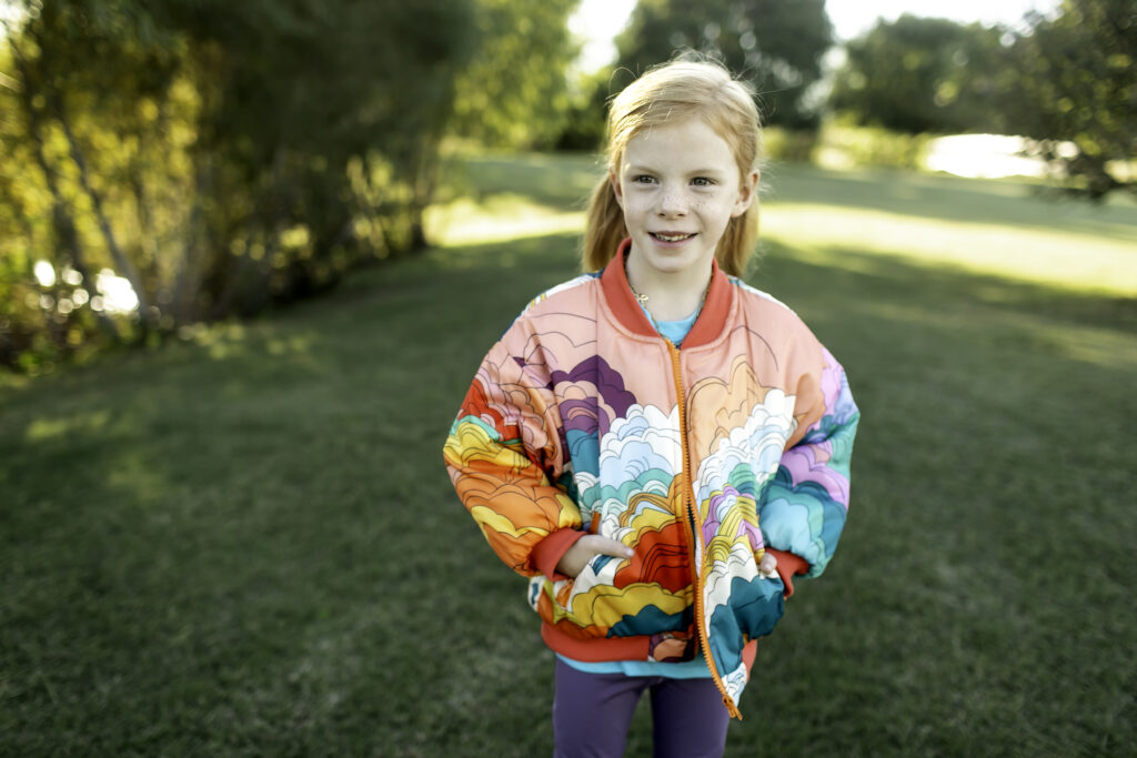 6-year-old girl in a colorful jacket, enjoying her birthday at the park