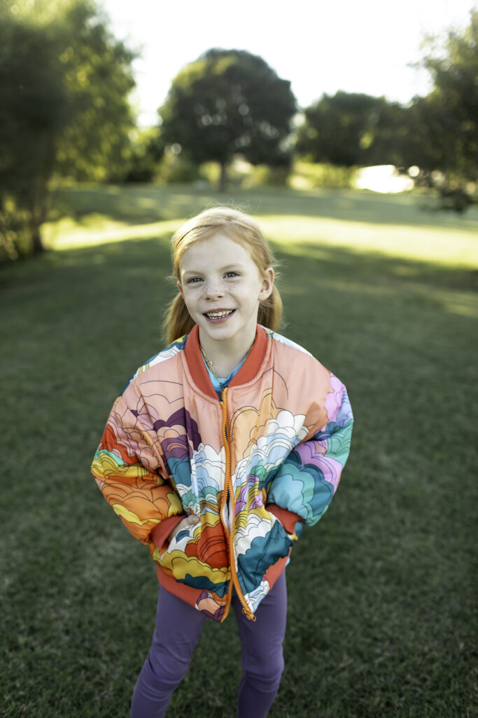 Birthday girl in a bright jacket, playing at the park