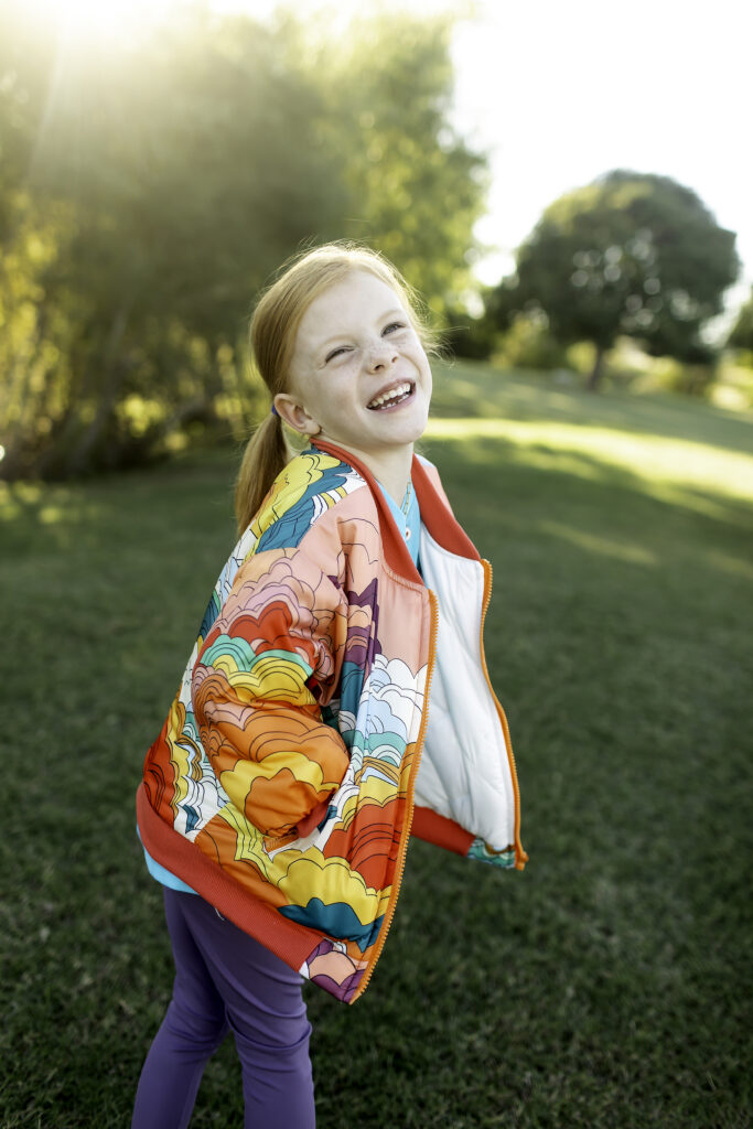 6-year-old girl in a colorful jacket, smiling at the park