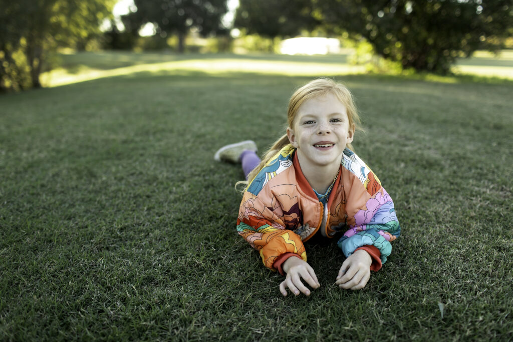 Joyful 6-year-old girl in a colorful jacket, exploring the park with birthday treats and laughter.