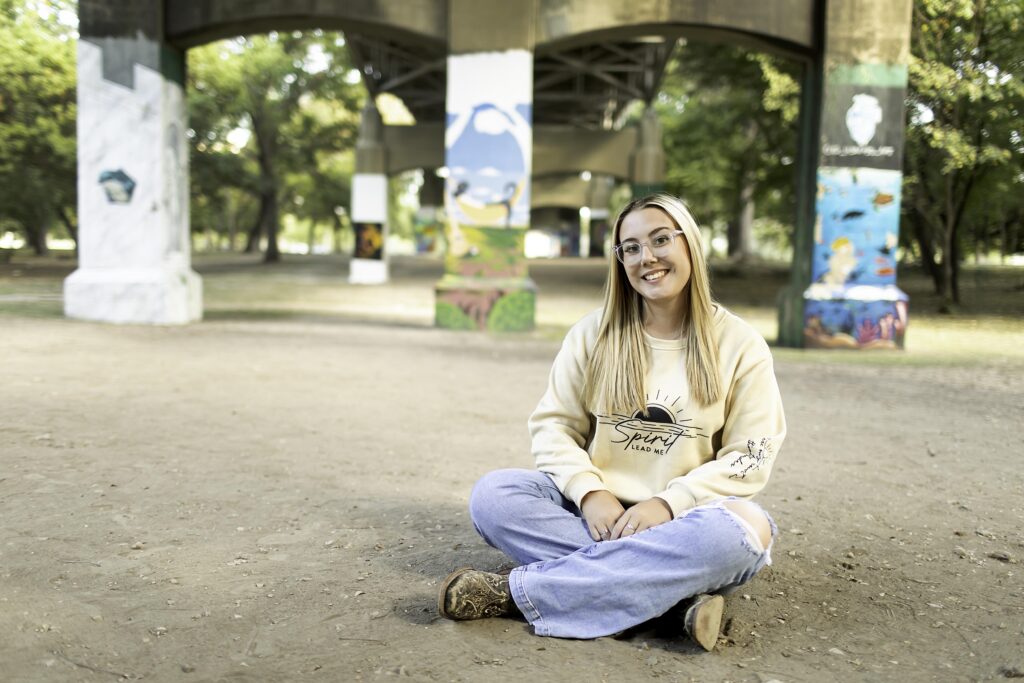 A senior girl poses confidently in an urban area, with the vibrant Fort Worth skyline providing a stunning backdrop during her photoshoot