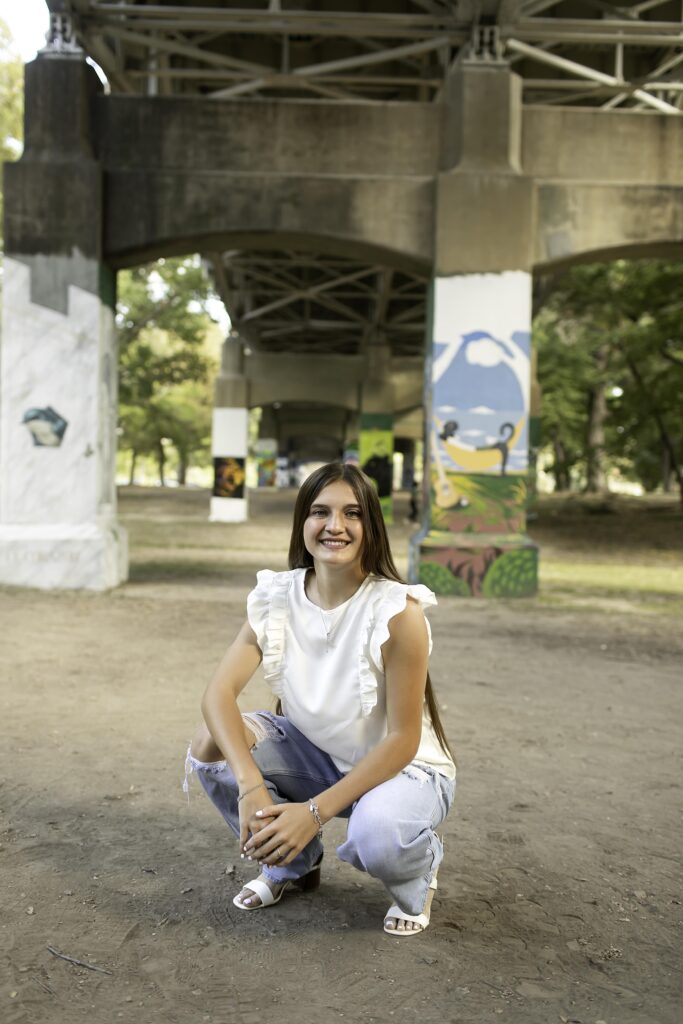 Casual portrait of senior girl standing on a pathway in a white shirt and blue jeans