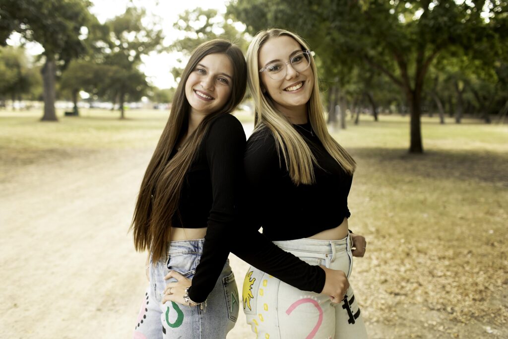 Captured in the heart of Fort Worth, two best friends rock their 2025 senior jeans, sharing a joyful moment together against the urban landscape