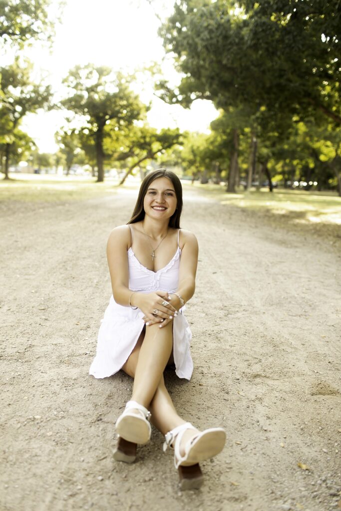 Senior girl posing gracefully in a flowy dress at Trinity Park, surrounded by tall trees