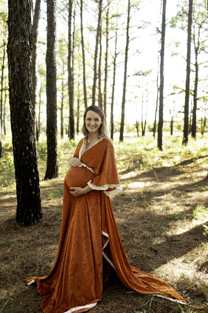 Expecting mother cradling her baby bump in a natural outdoor setting, captured in a peaceful maternity photoshoot