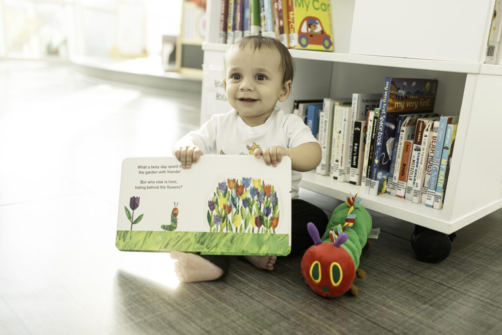 Captured at the Library in Fort Worth, TX, a little one enjoys their 1st birthday surrounded by colorful books, marking this special milestone with a thoughtful photoshoot