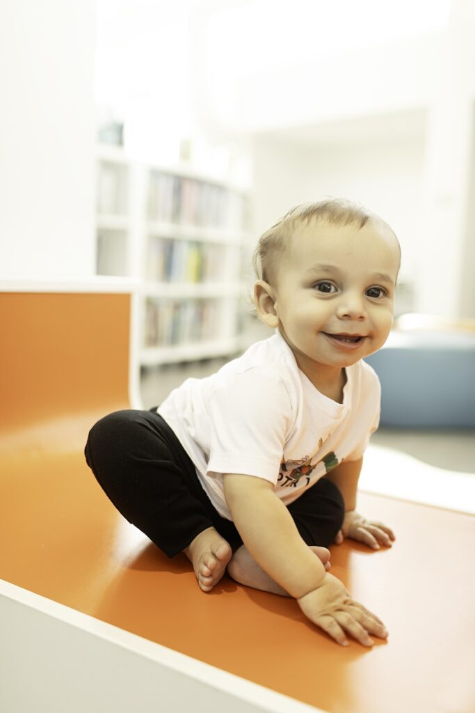 A 1-year-old enjoys their special day at the Library in Fort Worth, TX, posing for a photoshoot surrounded by shelves, creating a timeless memory for their milestone birthday