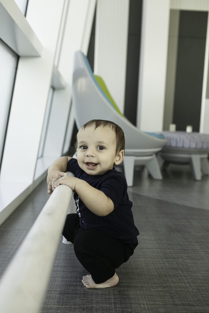 A little one enjoys their 1st birthday photoshoot at the Library in Fort Worth, TX, posing playfully with books in the background, capturing their milestone moment