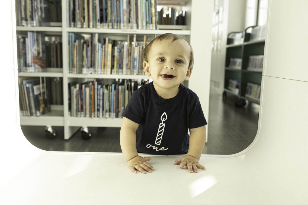 A 1-year-old celebrates their milestone at the Library in Fort Worth, TX, with a joyful photoshoot surrounded by books and educational charm