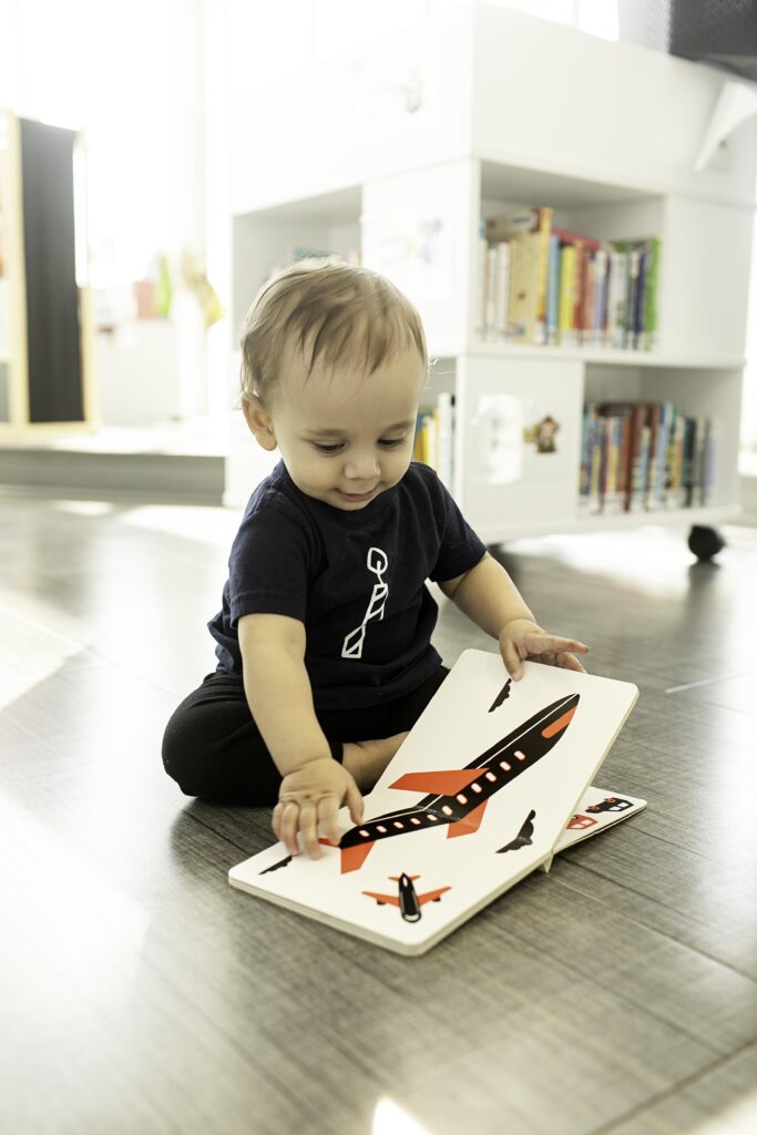 A 1-year-old smiles brightly as they sit among the shelves at the Library in Fort Worth, TX, creating a perfect memory of their first birthday in this special setting