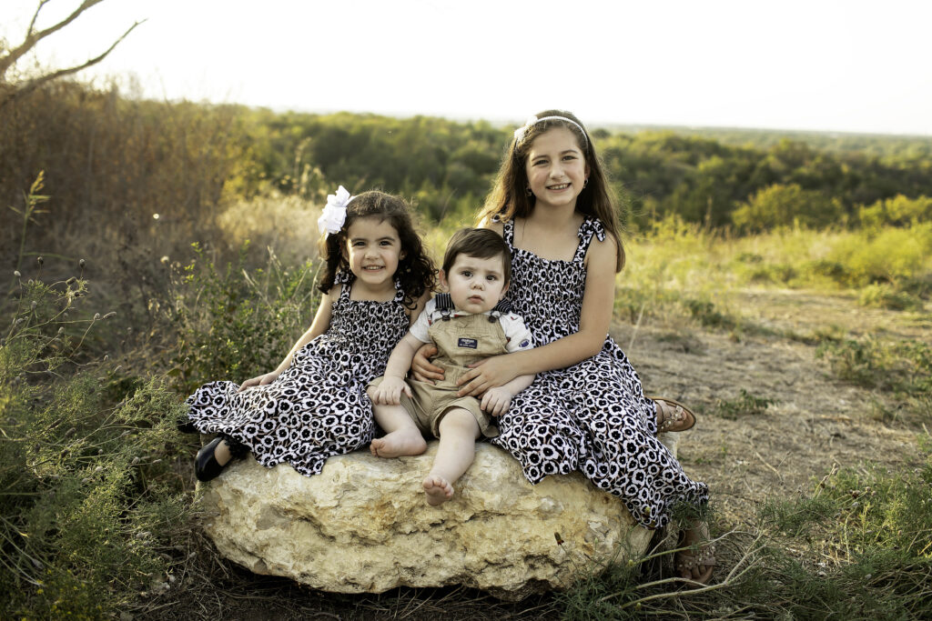 6-month-old boy with his three sisters, smiling together in a beautiful natural setting