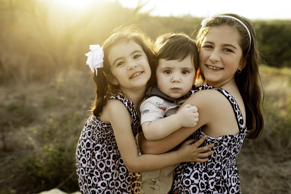 Adorable moment of a 6-month-old boy and his three sisters, laughing in the great outdoors