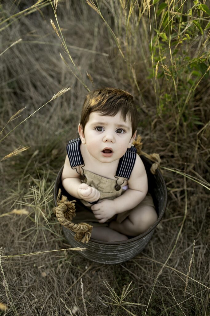 Adorable 6-month-old boy laughing joyfully on the grassy trails of Tandy Hills, captured in the sunshine