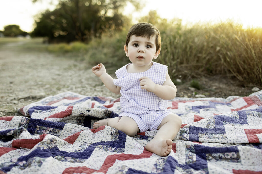 6-month-old boy sitting on the grass at Tandy Hills, surrounded by nature's beauty and a big smile