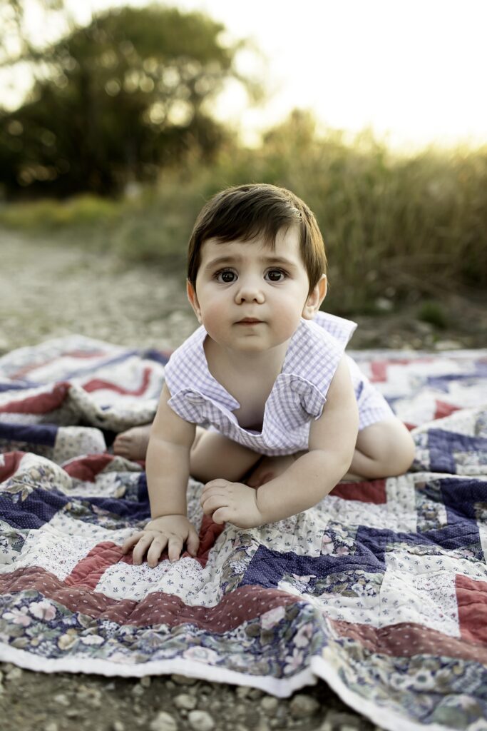 Playful moment of a 6-month-old boy on a blanket, with the vibrant Tandy Hills landscape surrounding him