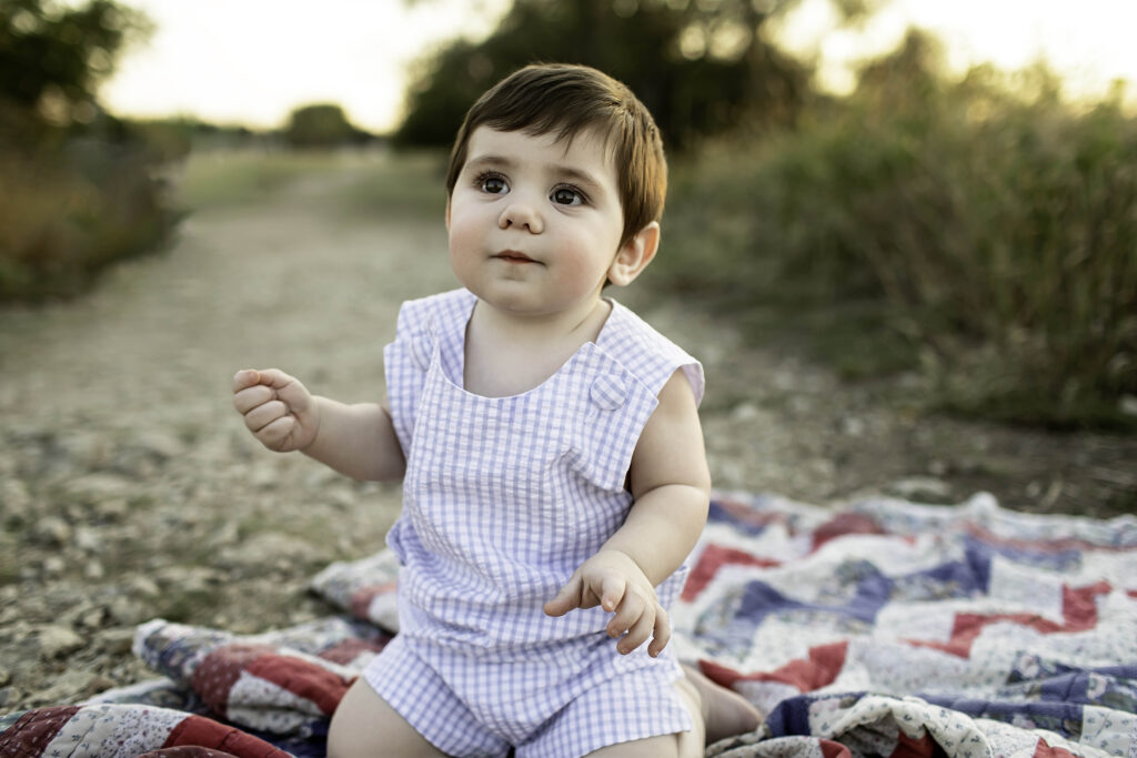 Close-up of a 6-month-old boy, enjoying a fun photoshoot amidst the lush scenery of Tandy Hills.