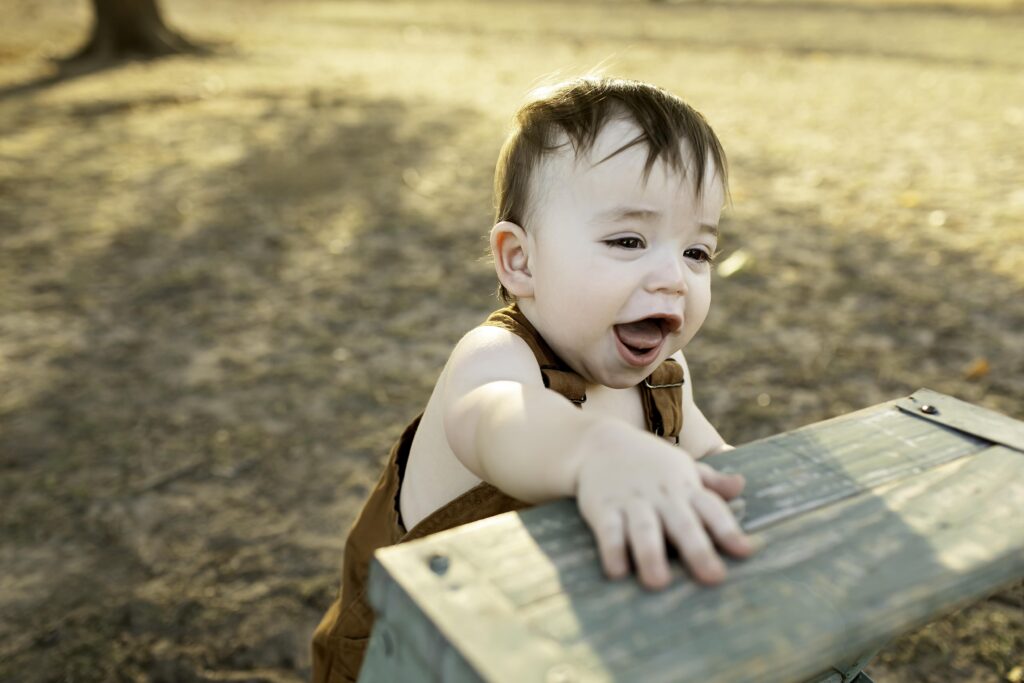 Boy in overalls standing on a mini ladder, looking up with curiosity and excitement