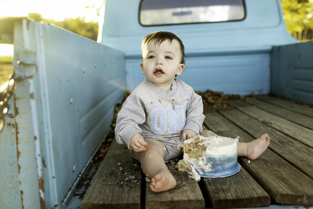 Birthday boy laughing while eating cake in the bed of an old truck, creating a joyful and playful moment