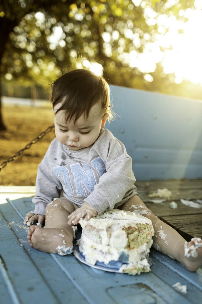 Adorable birthday boy enjoying his cake in the truck bed, with a big smile on his face