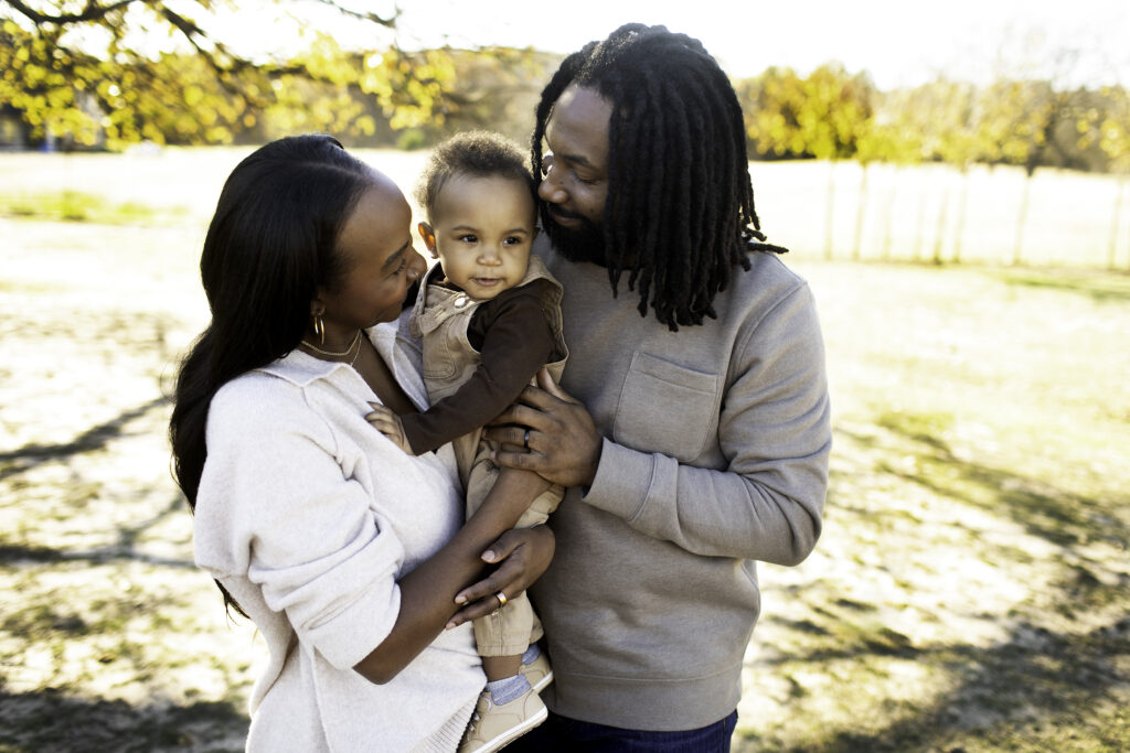 Mom and dad lovingly cuddling their one-year-old, sharing a sweet family moment during a Chunky Monkey Photography session