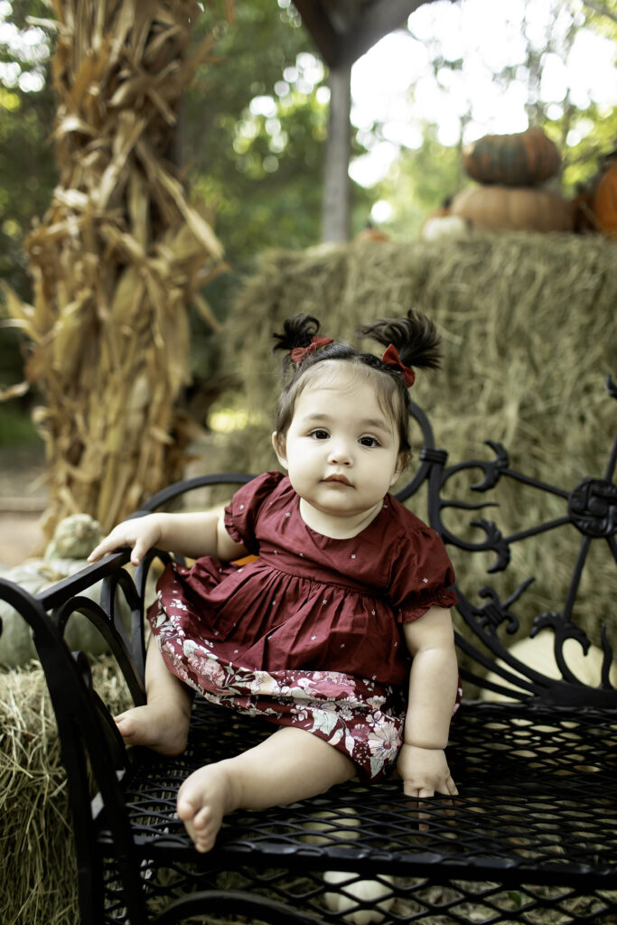 A 1-year-old enjoys their first birthday outdoors at Clark Gardens in Mineral Wells, TX, with stunning flowers and greenery creating a perfect backdrop