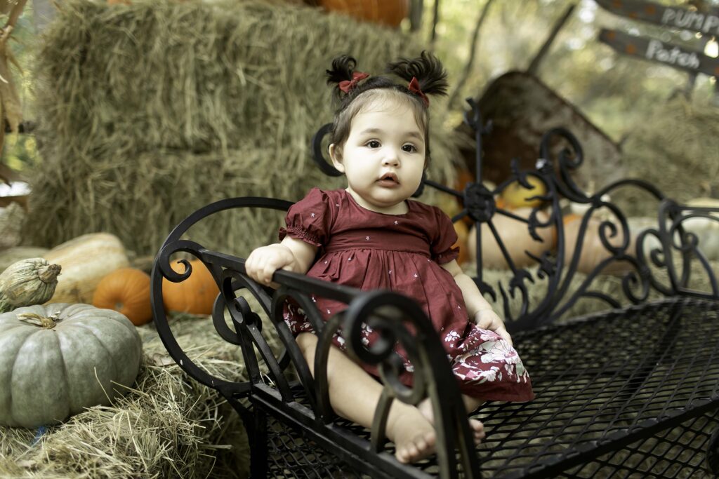 In the picturesque Clark Gardens in Mineral Wells, TX, a 1-year-old celebrates their milestone birthday, sitting on a bench surrounded by nature's beauty