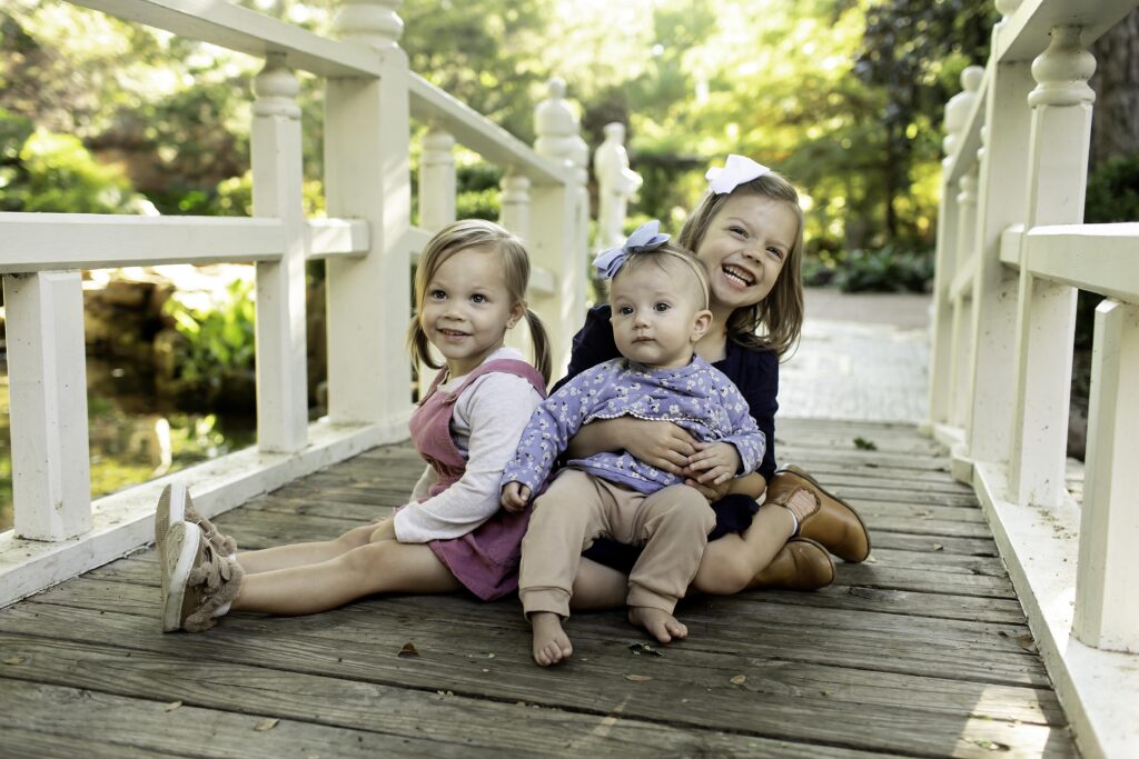 Three sisters laughing together in the beautiful, vibrant gardens of Chandor