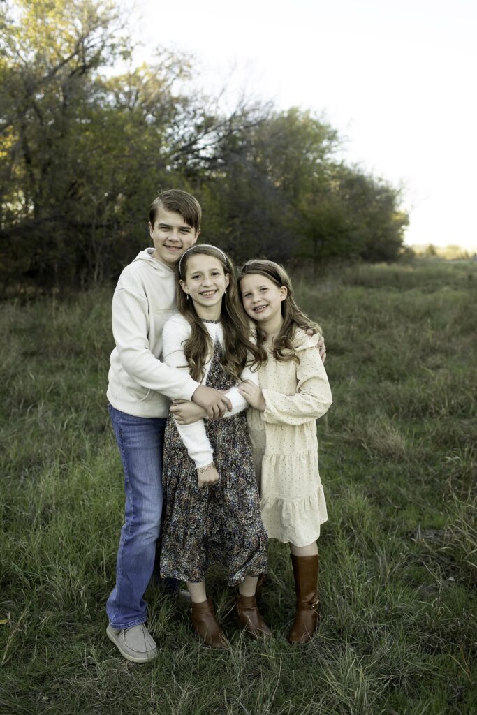 Three siblings enjoying a fun moment together at Northwest Community Park, surrounded by lush greenery