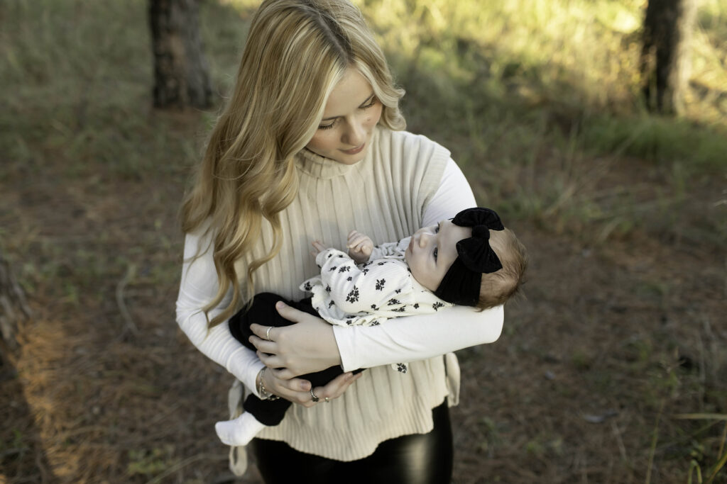 Surrounded by the beauty of Decatur’s pine trees, a mom cradles her newborn, both immersed in the calm and peaceful atmosphere of nature