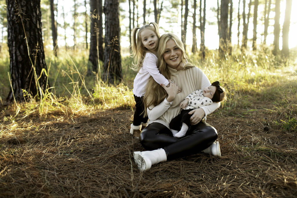 Amidst the towering pines of Decatur, a mom holds her newborn with one arm while her 3-year-old cuddles up to her, sharing a moment of family affection