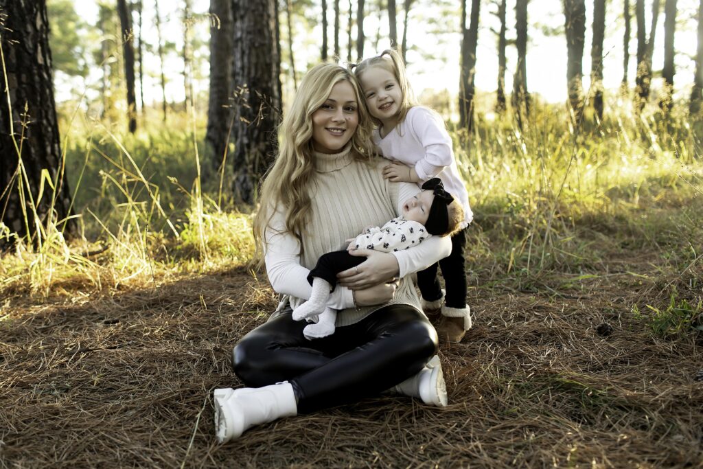 A mom holds her newborn close and lovingly embraces her 3-year-old among the pine trees of Decatur, the perfect moment of family love and nature