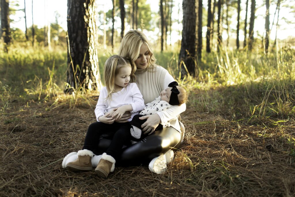 Family portrait session among the towering pine trees in Decatur, Texas, capturing the family surrounded by the natural beauty of the forest. The group smiles together, with the tall, lush pines creating a stunning backdrop, their needles filtering the sunlight and casting soft shadows on the ground. The peaceful, wooded environment adds a tranquil, rustic touch to the cherished family moment