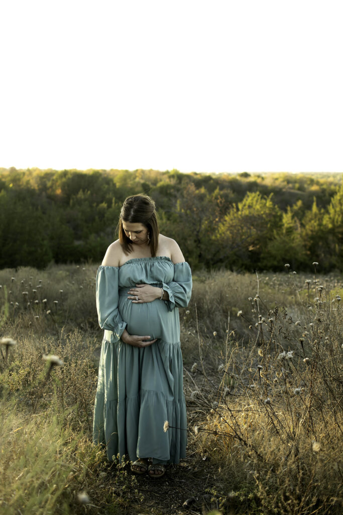 Pregnant woman surrounded by soft, dreamy lighting, showcasing her baby bump in a graceful maternity photoshoot