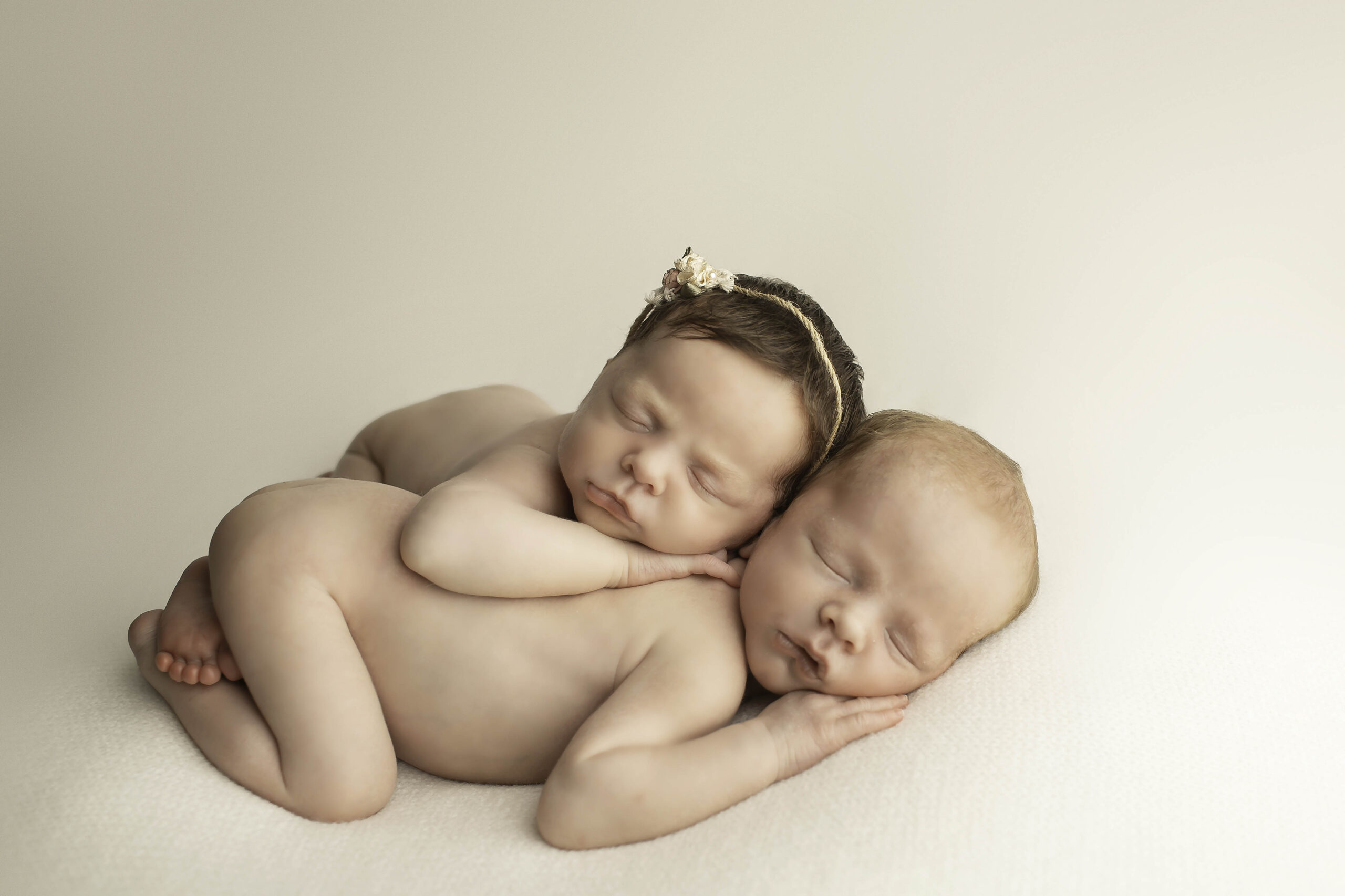 Twin newborn babies peacefully sleeping in matching blankets, captured in a serene setting during a Chunky Monkey Photography session