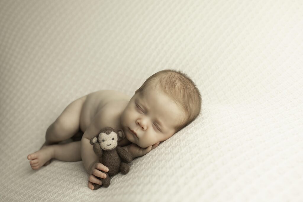 Newborn baby boy sleeping peacefully on a soft blanket during a Chunky Monkey Photography session