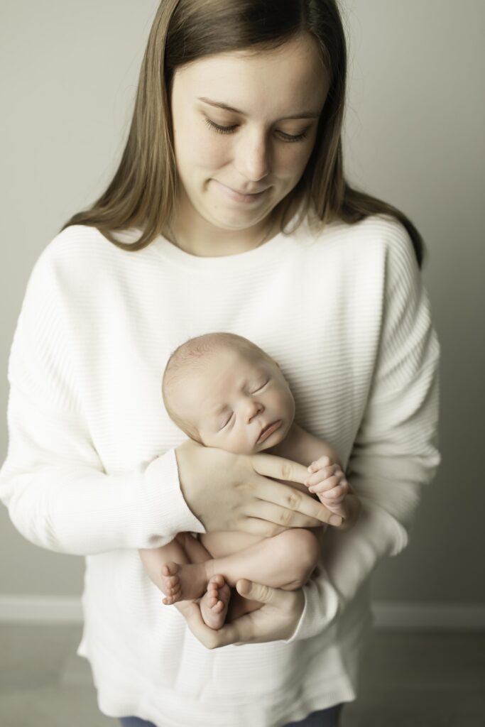 Newborn boy resting in his mom's arms, while dad looks on with a loving gaze