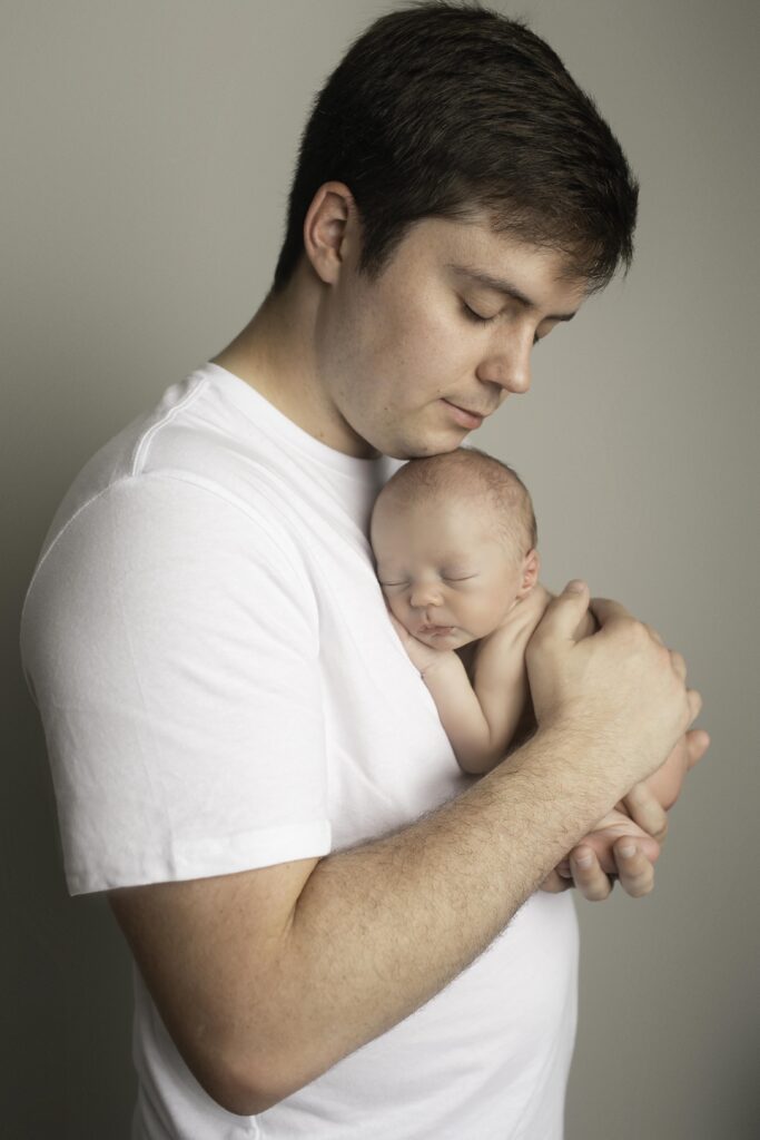 Dad holding newborn boy in his arms, creating a beautiful connection between father and son