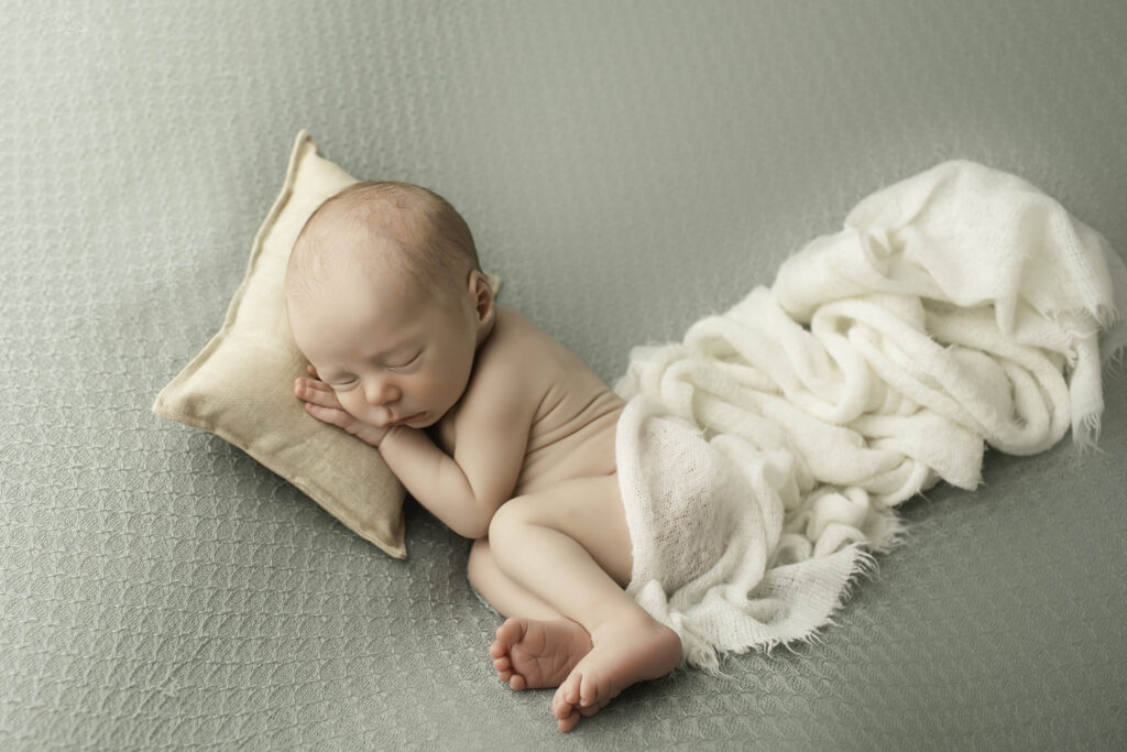 Newborn baby boy peacefully sleeping in a soft blanket during his studio photoshoot