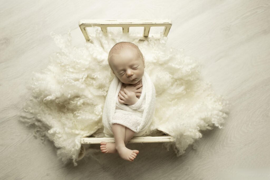 Newborn baby boy wrapped in a soft blanket, laying on fun themed props, adding charm to his session