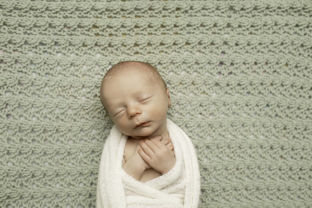 ewborn baby boy peacefully sleeping on a soft, neutral blanket in the studio