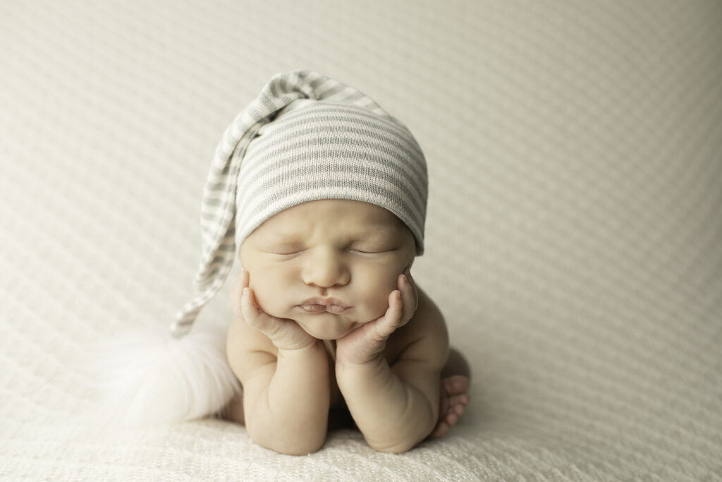 Tiny newborn baby boy resting on a soft blanket with a cute knit hat, captured during a Chunky Monkey session