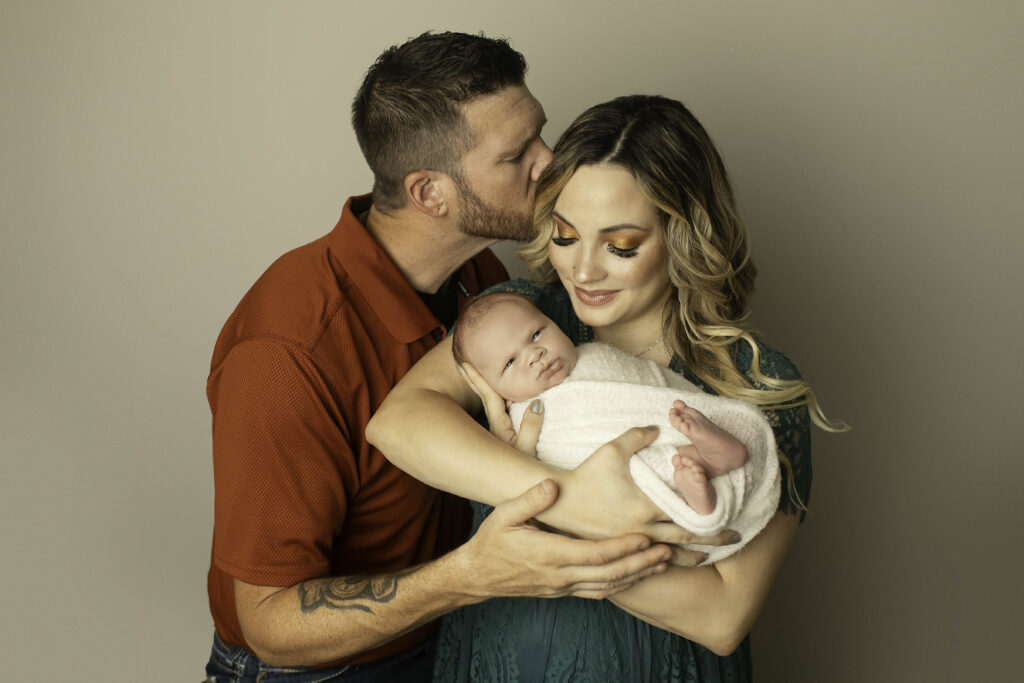 Parents and their newborn son posing together, sharing a sweet family moment full of love and connection