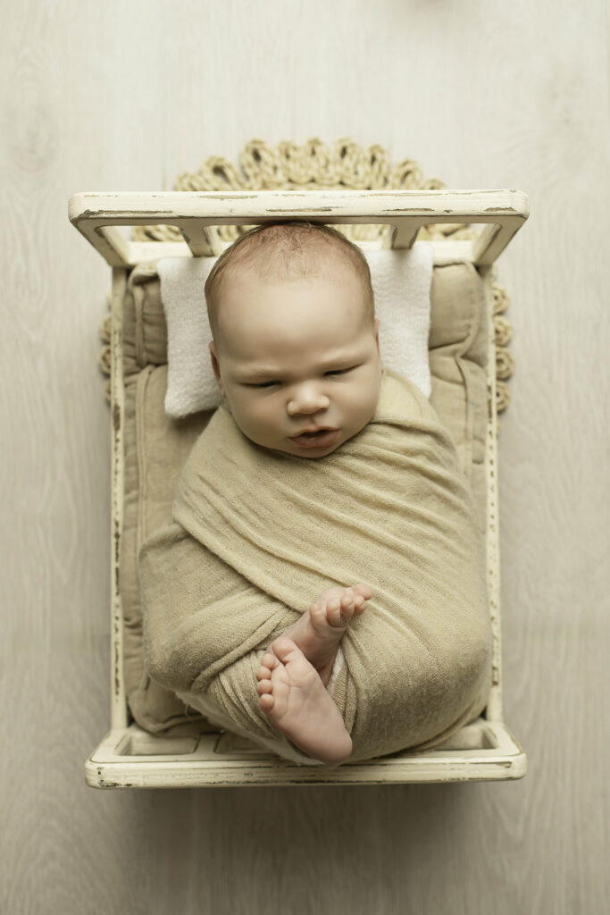 Newborn boy peacefully sleeping in a cozy blanket, captured in soft studio lighting