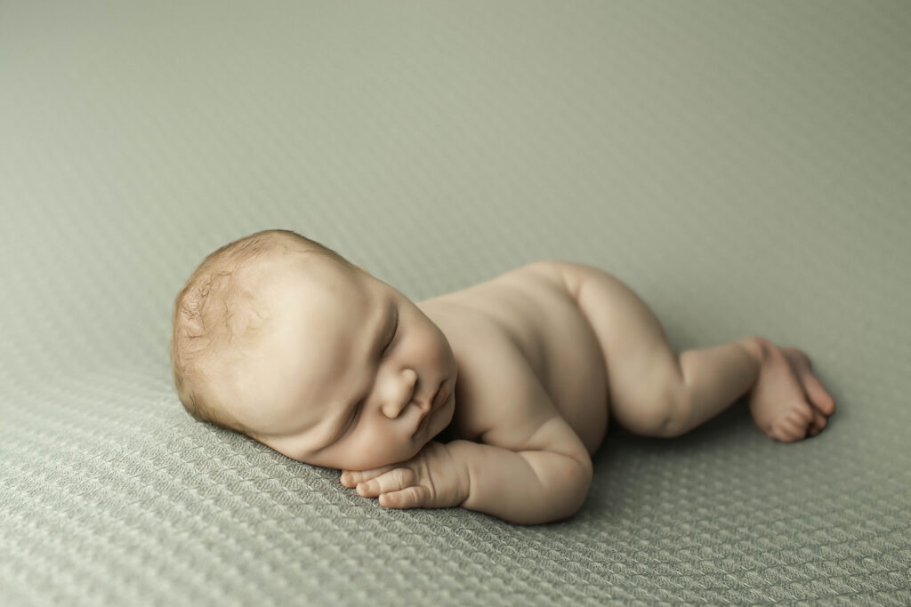 Sweet moment of a newborn boy sleeping soundly in a delicate, neutral-toned setup