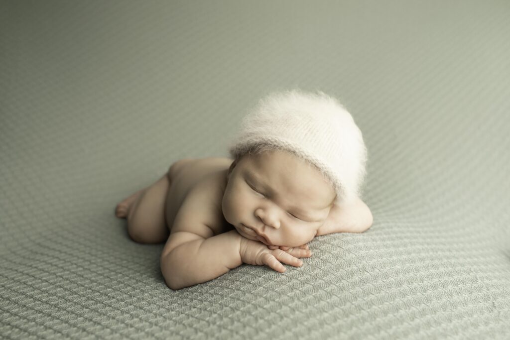 Newborn boy with his eyes closed, peacefully resting on a plush blanket in the studio